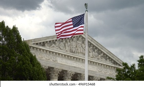 WASHINGTON, DC - MAY, 2014:  US Supreme Court, Stormy Sky, American Flag.  Equal Justice Under Law Engraving Is Seen Over Portico