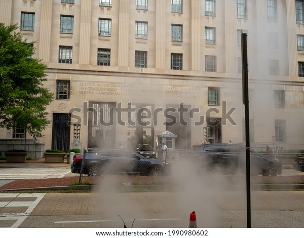 Washington DC, USA - 07-08-2019: smoke from\
underground in the street by the Department of Justice building in\
Washington DC