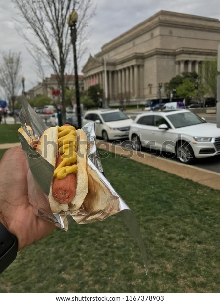 Washington D.C. USA – April\
11, 2019: many tourist enjoy hotdogs from street vendors in\
Washington D.C.