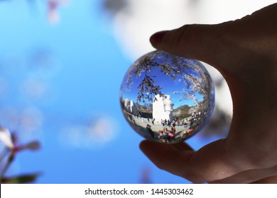 Washington, DC / USA - April 3, 2017: A Woman Takes A Photo Of The Martin Luther King, Jr. Memorial During Cherry Blossom Season Through A Glass Crystal Lens Ball.