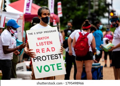 Washington, DC, USA - August 1, 2020: A man holds a sign urging protesters to act and register to vote at the Demand DC rally and march, sponsored by The Palm Collective