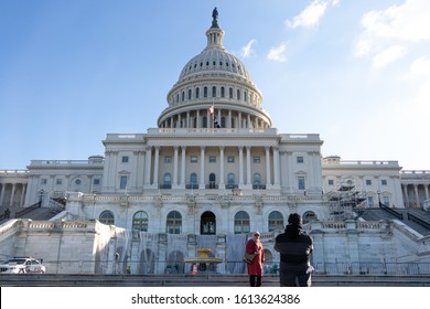 WASHINGTON, DC, USA - December 11, 2019: Couple Take Photos In-front Steps To The US Capitol Building, West Side On Sunny Day. 