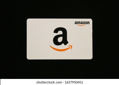 Washington, D.C. / USA - Feb. 26, 2020: An Amazon.com gift card is against a plain black background. The card can be used to make purchases on the Amazon website, a company founded by Jeff Bezos.