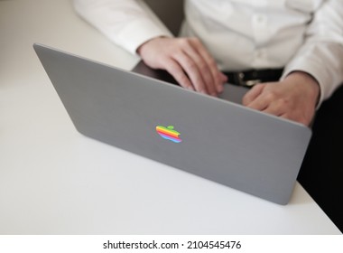 Washington DC, USA, January 10, 2021: Office Worker With White Shirt And Black Trousers Working On A Apple Laptop Computer Bearing A LGBTQ Rainbow Apple Logo On The Back Of The Cover