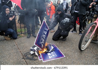 Washington, D.C., USA - January 20, 2017:  A self-described anti-fascist, anti-Donald Trump protester burns Trump-Pence signs shortly before an unauthorized march through downtown on inauguration day.