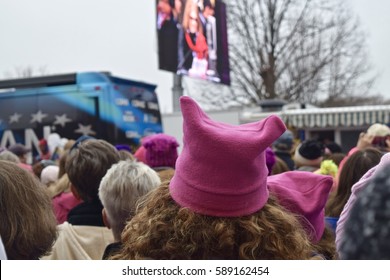 Washington D.C., USA January 21, 2017- Women's March on Washington: Protesters gather in a large crowd near a monitor projecting the rally, a protester wearing a pink "pussy hat" is featured.