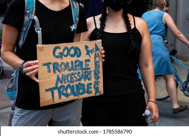 Washington, DC, USA - July 25, 2020: A protester holds a sign quoting the late Congressman John Lewis: "Good trouble, necessary trouble" at the March Against Trump's Police State