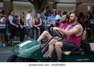 Washington, DC - USA - June 08, 2019: LGBT+ Gay Pride Colorful And Happy Parade On 17th Street NW In The Nation Capital. Portrait Of A Gay Couple Of Males With Beard On A Small Electric Car.  