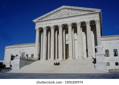 Washington, DC - USA - March 22, 2017: Facade, Stairs And Columns Of The Main Entrance Of The Supreme Court (SCOTUS) Building And Blue Sky And Three Persons Sit On The Stairs. 