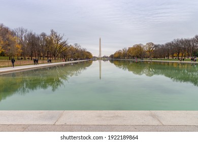 Washington DC, USA - November 30, 2019: US Washington Monument and Capitol reflecting in a pond calm water surface with dry trees around