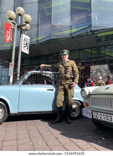 Washington, DC / USA - November 9, 2019: Man in NVA East\
German uniform in front of a Trabant car at the International Spy\
Museum as part of the 30th anniversary of the Fall of the Berlin\
Wall. 