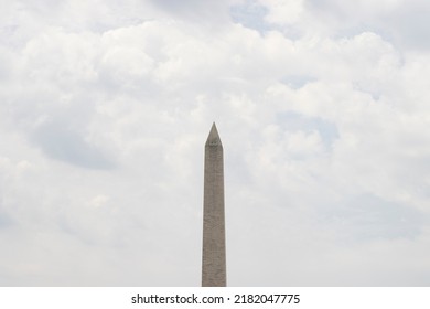 The Washington Monument, an obelisk towering over Washington, DC, isolated against a cloudy sky. - Powered by Shutterstock