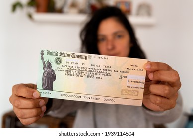 Washington, Usa - 10 March 2021: Woman Holding Stimulus Check And Face Mask On Black Background, Concept Of Federal Financial Help Given To Stop Economic Crisis Of Covid19 Pandemic