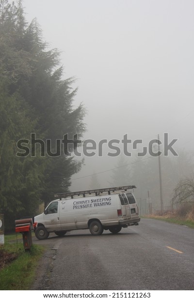 WASHINGTON - USA, April 04 2022: A chimney\
sweeping pressure washing service van runs on rural American roads.\
with fog in the\
morning.