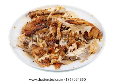 Waste and bones from grilled fried chicken on plate. Isolated on white