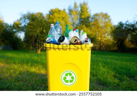 Waste container with garbage in park. Waste sorting, Recycling. Bottle in trash bin container. Garbage Sorting. Trash bin bucket. Plastic bottles in trash can. Garbage container with plastic bottles.