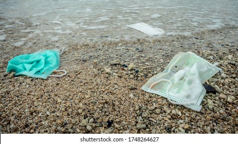 Waste during COVID-19. Discarded to ocean coronavirus single-use face masks. Environmental and coast plastic pollution. Trash in the beach threatening the health of oceans.