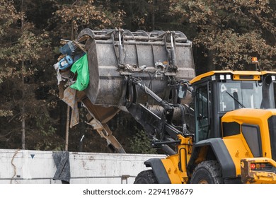 Waste loading operation, loader dumping trash in a truck on a site for the disposal of waste materials