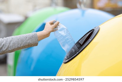 Concepto de reciclaje de residuos. Señora irreconocible que lanza la botella de plástico en el contenedor amarillo de la papelera de reciclaje al aire libre, clasificando la basura, disfrutando de la vida de cero residuos, Imagen recortada con enfoque selectivo
