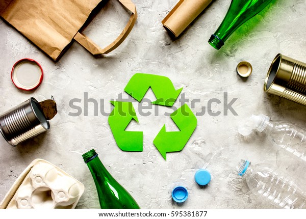 waste recycling symbol with garbage on stone\
background top view