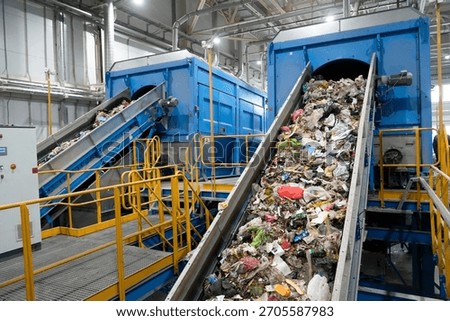 A waste sorting facility operates by separating various types of refuse for recycling. Conveyors carry debris, showcasing an assortment of discarded materials in a clean industrial environment.