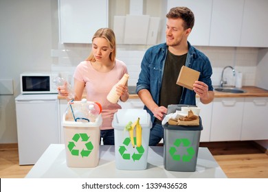 Waste sorting at home. Smiling young family putting plastic, paper, other waste in garbage bio bins in the kitchen - Powered by Shutterstock