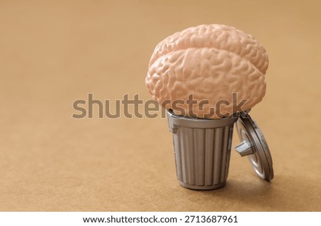 Wasted Intelligence: Human Brain Resting on Silver Trash Can