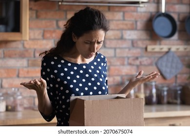Wasted money. Irritated latin woman courier service client receive broken damaged goods in delivery box. Angry young lady get wrong order in parcel from online shop disappointed with product quality