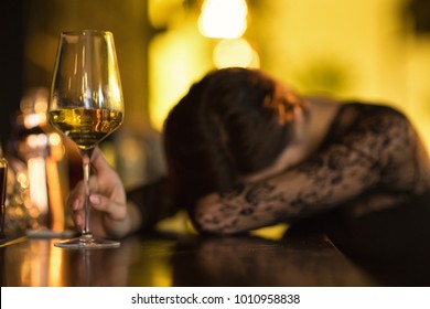 Wasted woman sleeping on the bar counter after drinking too much alcohol selective focus on a glass of wine copyspace booze alcoholic problem addicted addiction lifestyle party event depression - Powered by Shutterstock