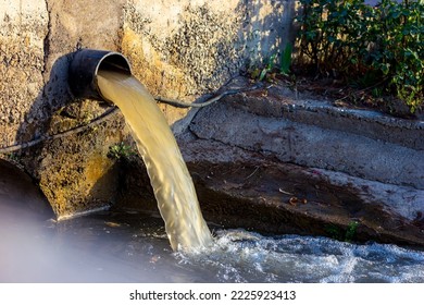 Wastewater sewage pipe dumps the dirty contaminated water into the river. Water pollution, environment contamination concept