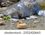 Wastrel brown paper container, Waste and garbage on street with hole, Birds pinched the trash with refuse, Black plastic bin bags on street before the officer to collect, Amsterdam, Netherlands.
