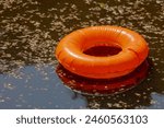 Wastrel from King’s Day (Koningsdag) Selective focus of garbages and rubber ring in the canal after party, City is bursting with orange, Save the world and stop global warming, Amsterdam, Netherlands.