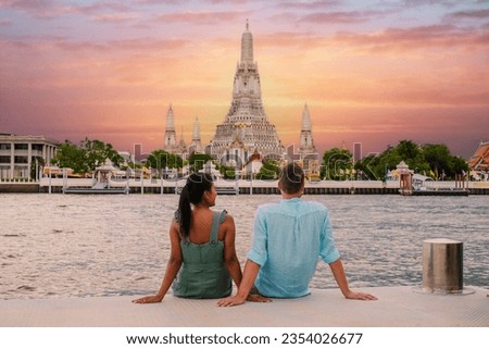 Wat Arun Temple Bangkok during sunset in Thailand. Chao Praya River at sunset. a couple of men and a woman are on a city trip to Bangkok Thailand watching sunset by the river