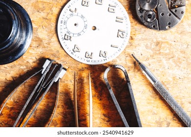 watch dial, tweezers, magnifier, and other tools lie on a wooden workbench, showcasing the careful arrangement needed for precision tasks in horological craftsmanship - Powered by Shutterstock