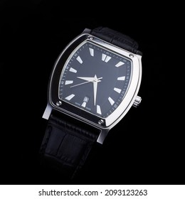A watch with a leather strap on a black background.                             