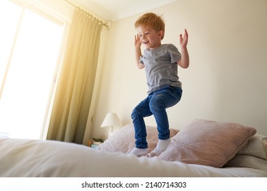 Watch Me Jump Higher Each Time. Shot Of A Young Boy Jumping On A Bed At Home.