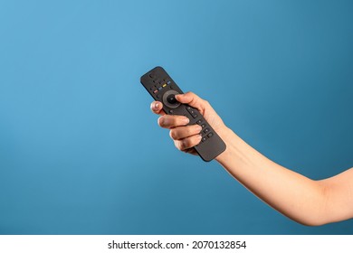 Watch new TV series and movies at home on streaming services, the TV remote control is in a female hand, switch channels. Photo on a blue background - Shutterstock ID 2070132854
