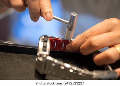 A watch pin being installed into the watch band with a hammer and a watch band holder. Close up - Powered by Shutterstock