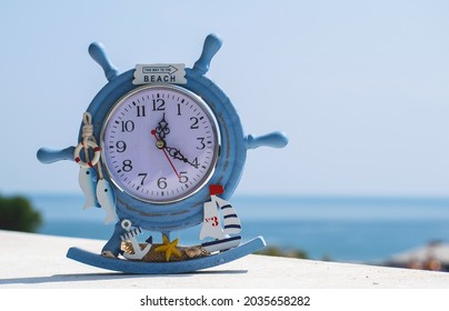 A watch, a souvenir from the summer vacation. On the clock is the text "This way to the beach". Blue sea in the background.