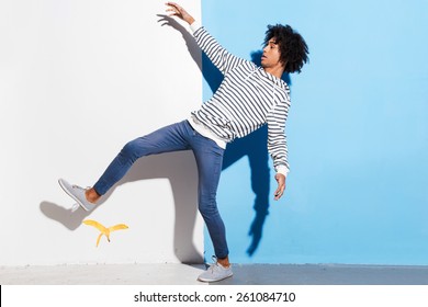 Watch Your Step! Handsome Young African Man Slipping Against Colorful Background 