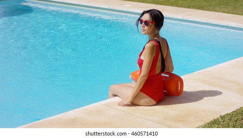 Watchful Lifeguard Sitting At Side Of Pool