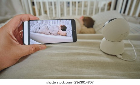 Watching a child sleeping in a room from a phone through a camera - Powered by Shutterstock