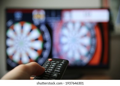 Watching Dart On TV. Finger On The Volume Up Button On The Remote. (Focus On The Remote)