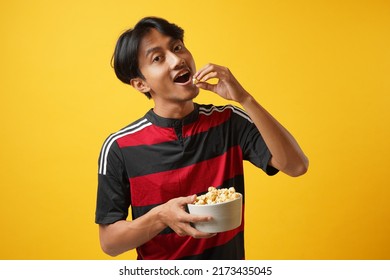 Watching Football Match. Surprised Young Asia Man Eating Popcorn With Red Tshirt