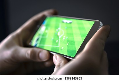 Watching Football And Sport Stream With Mobile Phone. Man Streaming Soccer Game Live, Video Replay Or Highlights Online With Smart Device. Sports Fan And Program Of Tv Network In Smartphone Screen. 