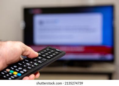 Watching News Channel On TV. Thumbs Up On The Remote's Volume Up Button. Remote Control In Selective Focus. Breaking News Concept.