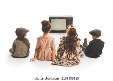 Watching tv. Group of fashionable kids, children sitting in front of retro tv set isolated on white background. Friendship, hobbies, art, eras comparison and children emotions - Powered by Shutterstock