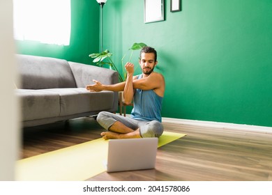 Watching A Video Tutorial. Happy Young Man Doing Stretching Exercises While Following An Online Home Workout Video