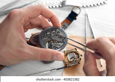 Watchmaker hands repairing mechanism of old watch closeup