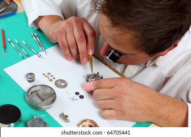 Watchmaker in his workshop repairing a wrist watch. Intentional shallow depth of field.